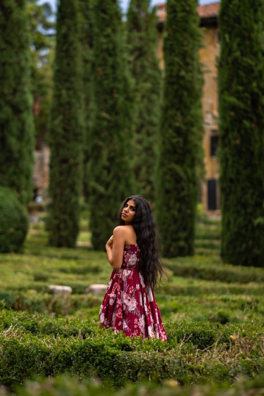 Vandana in a red floral dress in an Italian garden