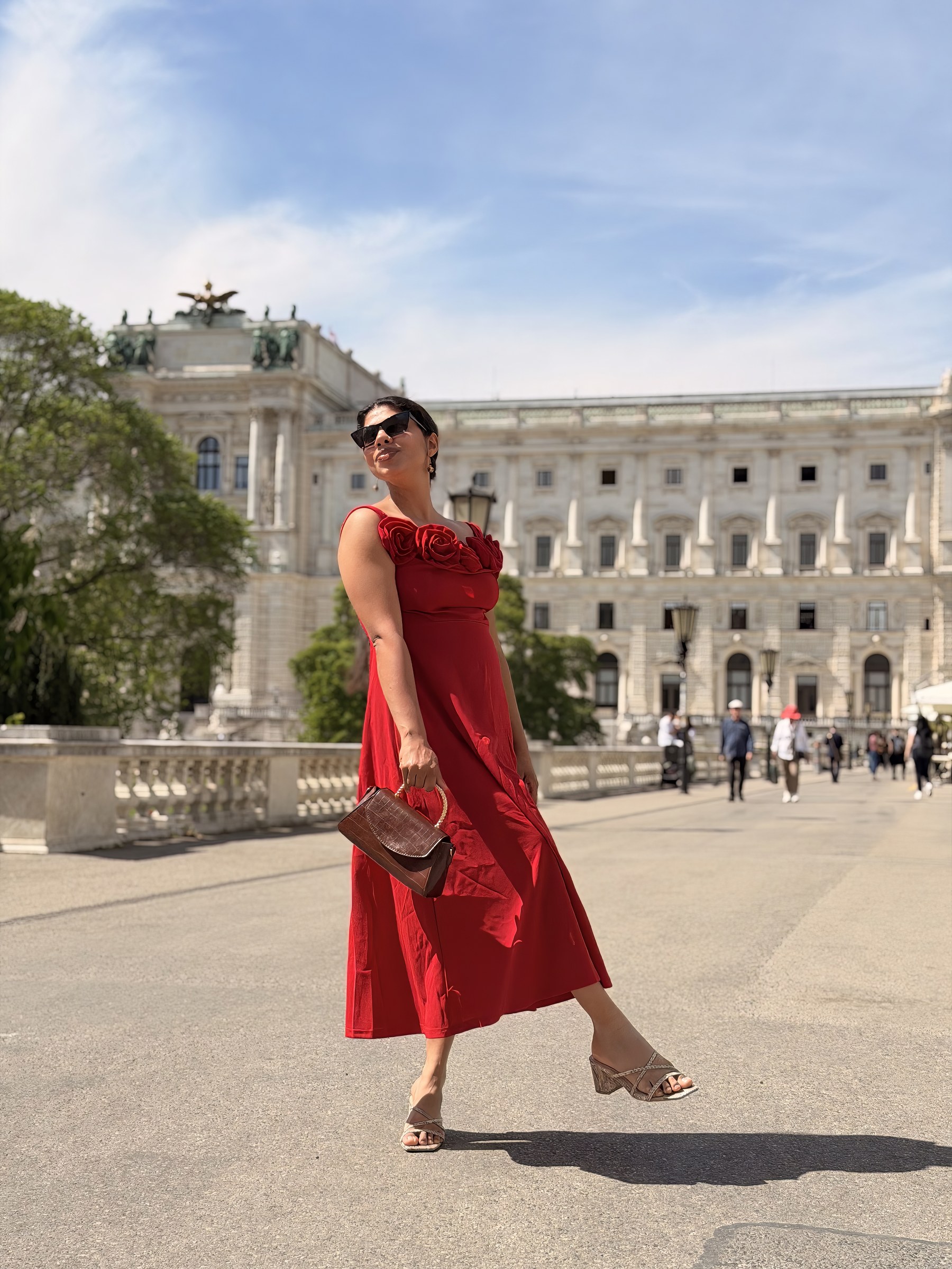 Vandana in a red dress outside a grand European building